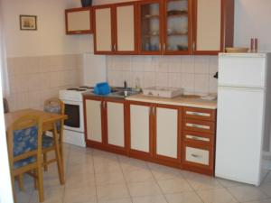 a kitchen with wooden cabinets and a white refrigerator at Jelena Apartment in Tkon