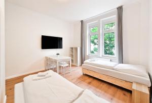a white room with two beds and a tv at RAJ Living - 3 and 4 Room Apartments in Duisburg