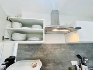 a kitchen with a sink and white cabinets with dishes at SUPERBE DUPLEX DESIGN NEUF 2 CHAMBRES, CLIMATISE TOUT CONFORT, FACILE D,ACCES STATIONNEMENT GRATUIT in Marseille