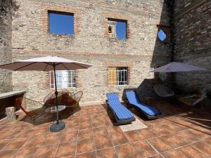 普埃布拉的住宿－Hostal Casa De Arcos，砖砌建筑中带椅子和遮阳伞的庭院