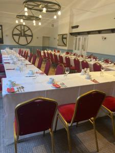 Habitación grande con una mesa larga con sillas rojas. en Saracens Head Hotel by Greene King Inns en Towcester