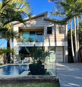 a house with a swimming pool and palm trees at The Palm - Beachside Home with Heated Pool & Cinema in Mudjimba