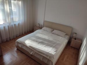a bedroom with a bed with white sheets and a window at Apartman Tedi in Zlatibor