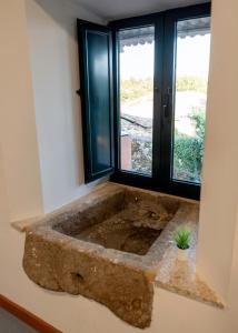 a large stone tub in a room with a window at A Bruxiña de Toldaos in Pantón