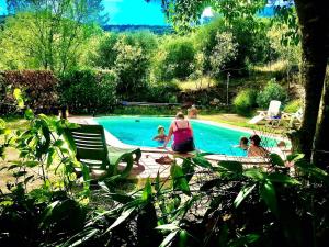 una mujer y dos niños sentados junto a una piscina en B&B Il Casale Del Ginepro, en Migliano