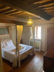 1 dormitorio con 1 cama con cortinas y lámpara de araña en B&B Il Casale Del Ginepro, en Migliano