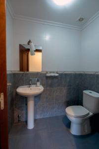 a bathroom with a sink and a toilet and a mirror at A Bruxiña de Toldaos in Pantón