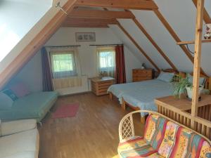 a attic room with two beds and a couch at Négy Évszak Apartmanház in Zalakaros