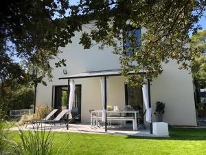 a white house with a table and chairs on a patio at Villa piscine plein sud proche Uzes in Arpaillargues-et-Aureillac