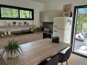 a kitchen with a wooden table and a white refrigerator at Villa piscine plein sud proche Uzes in Arpaillargues-et-Aureillac