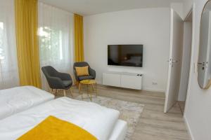 a bedroom with a bed and two chairs and a tv at Appartement mit Balkon Westfalenhalle und Universität fußläufig in Dortmund