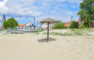 a umbrella in the sand on a beach at Nice Apartment In Nowe Warpno With Wifi in Nowe Warpno