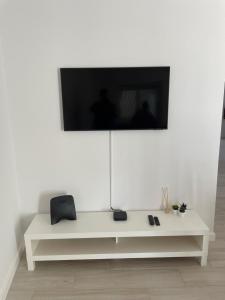 een witte tafel met een tv aan een witte muur bij A Minha Praia in Quarteira