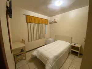 a small bedroom with a bed and a desk at Hotel Blanner in Charqueadas