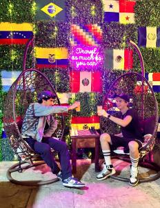 two men sitting in wicker chairs in front of a wall at Llaqta Wasi in Lima