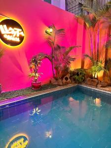 a swimming pool in front of a pink wall with plants at Llaqta Wasi in Lima