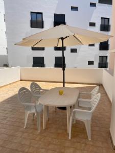 a white table and chairs with an umbrella at A Minha Praia in Quarteira