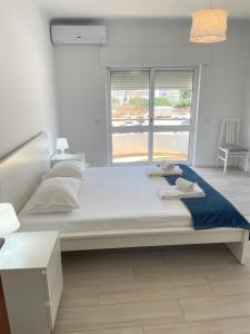 Cette chambre comprend un grand lit et une fenêtre. dans l'établissement A Minha Praia, à Quarteira