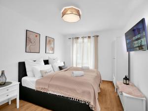 a white bedroom with a large bed and a tv at INhome 3x TV - Terrasse - Küche - Parken- Netflix in Crailsheim