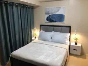 a bedroom with a large bed with green curtains at Cozy 2 Bedroom Condo with Balcony for Rent in Iloilo City