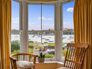 a window with two chairs and a view of a harbor at Waterside Cottage in Saltash