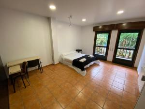 a bedroom with a bed and a desk and windows at Albergue O Beque in Moaña