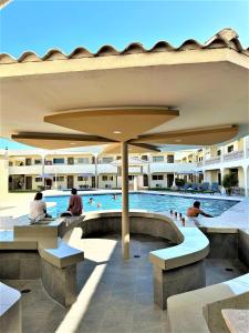 a swimming pool with people sitting under an umbrella at KAVIA MEOQUI HOTEL & SUITES in Meoqui