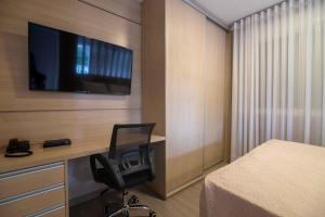 a bedroom with a desk with a chair and a television at Bela Vista Hotel & Flat in Porto Alegre
