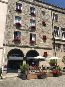 um edifício com mesas e guarda-chuvas à sua frente em Logis Maison Vauban - Hotel St Malo em Saint Malo