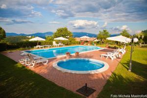 una gran piscina con sillas, mesa y sillas en Agriturismo Poggio Paradiso, en Mengara