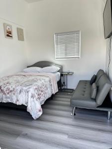 een slaapkamer met een bed en een bank erin bij Tiny house in the heart of MOVAL private freeparking Netflix in Moreno Valley