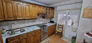 a kitchen with wooden cabinets and a sink at La Xana del Arbeyal - Apartamento ideal Para 3 pax in Gijón