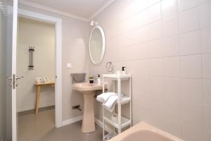 Baño blanco con lavabo y espejo en STAY Benavente, en Oviedo