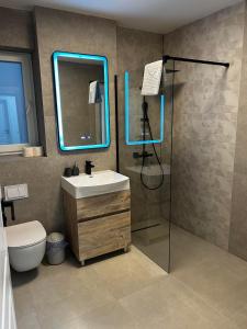 baño con lavabo y ducha con luces azules en Traian Taranu Apartment en Suceava