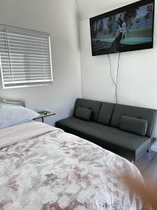 een slaapkamer met een bank en een tv aan de muur bij Tiny house in the heart of MOVAL private freeparking Netflix in Moreno Valley