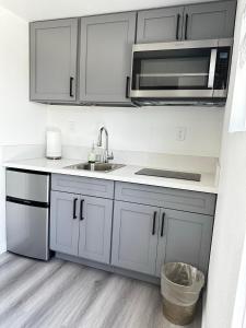 a kitchen with white cabinets and a sink and a microwave at Tiny house in the heart of MOVAL private freeparking Netflix in Moreno Valley