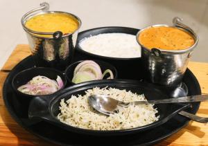une assiette noire avec du riz et un bol de nourriture dans l'établissement Around Stays Hostel Rishikesh, Tapovan, à Rishikesh