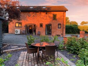 a patio with a table and chairs in front of a brick building at The Ash Loft in Audlem