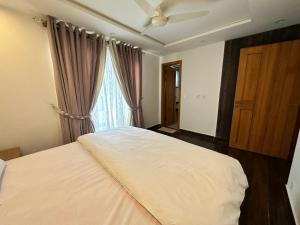 a bedroom with a large white bed with a window at 2 Bed Apartment near Gulberg in Lahore
