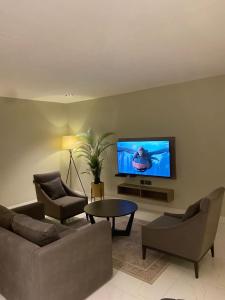 a living room with two couches and a flat screen tv at Knightsbridge Hotel & Suites in Abuja