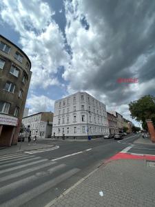 um edifício branco numa rua da cidade com um céu nublado em Small studio with entresol em Bydgoszcz