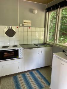a kitchen with white appliances and two windows at Ormanäs Stugby in Höör