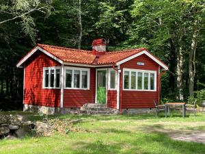 uma pequena casa vermelha no meio de um campo em Ormanäs Stugby em Höör