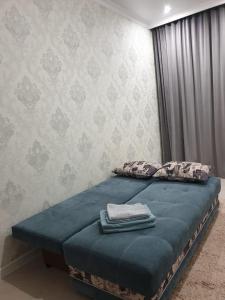 um quarto com uma cama com lençóis e almofadas azuis em Квартира в центре левого берега Астаны Туран, 46А em Taldykolʼ
