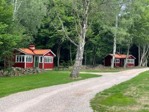 uma estrada de cascalho que conduz a uma cabina vermelha e branca em Ormanäs Stugby em Höör