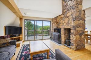 a living room with a large stone fireplace at Distinctive 4 bedroom townhouse, with outdoor hot tub minutes from the slopes Winterberry 4 in Killington
