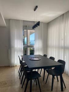 uma sala de jantar com uma mesa preta e cadeiras em Relax Sea View 3BR in Gordon Beach by Holyguest em Tel Aviv