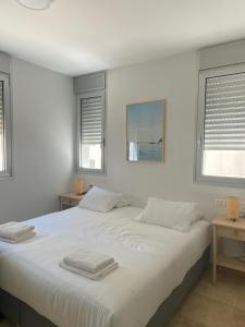 um quarto com uma grande cama branca com duas toalhas em Relax Sea View 3BR in Gordon Beach by Holyguest em Tel Aviv