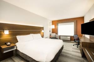Holiday Inn Express & Suites Sioux City North - Event Center, an IHG Hotel في Dakota Dunes: غرفه فندقيه سرير كبير وتلفزيون