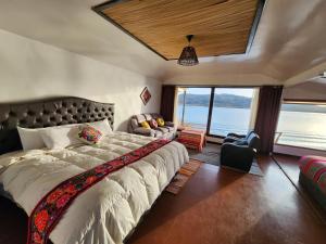 a bedroom with a large bed and a large window at Casitas del Titicaca Peru in Puno